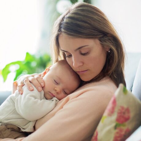 O mamă care ăși ține bebelușul pe piept pentru a ilustra câteva metode prin care poți să-ți adormi bebelușul mai ușor