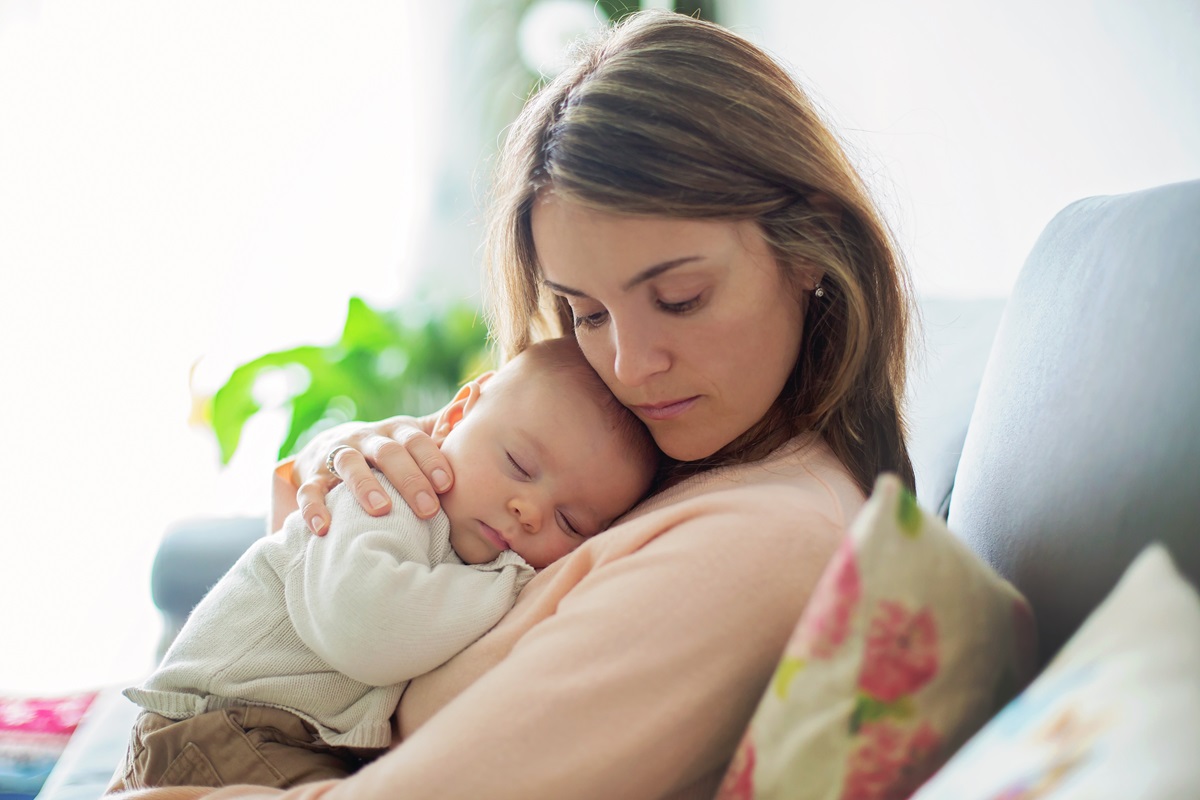 O mamă care ăși ține bebelușul pe piept pentru a ilustra câteva metode prin care poți să-ți adormi bebelușul mai ușor