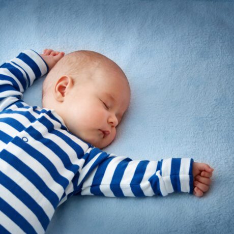 Un bebeluș care doarme cu mâinile ridicate