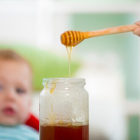 Bebeluș se uită la o lingură cu miere de albine