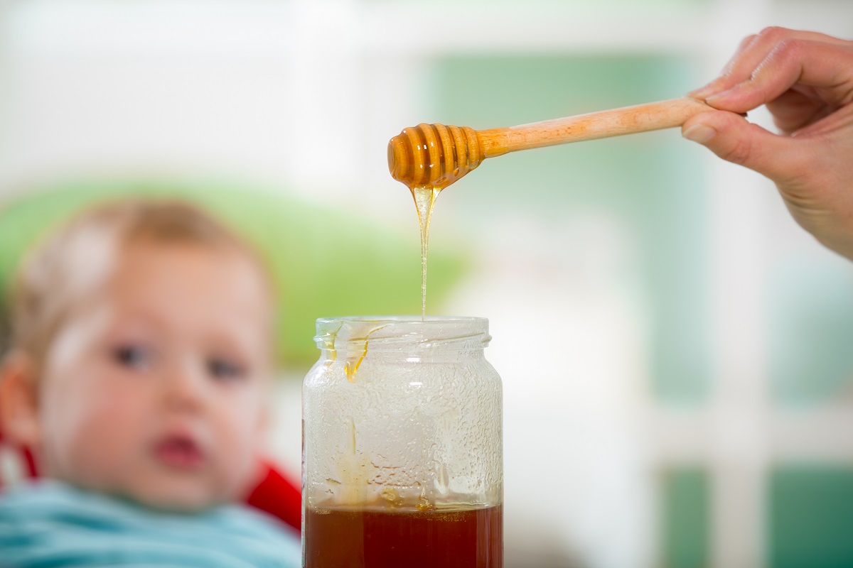 Bebeluș se uită la o lingură cu miere de albine