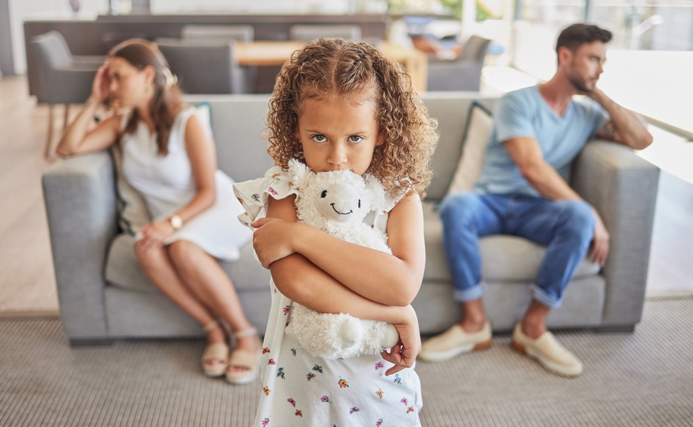 Fată tristă între doi părinți certați care stau pe canapea