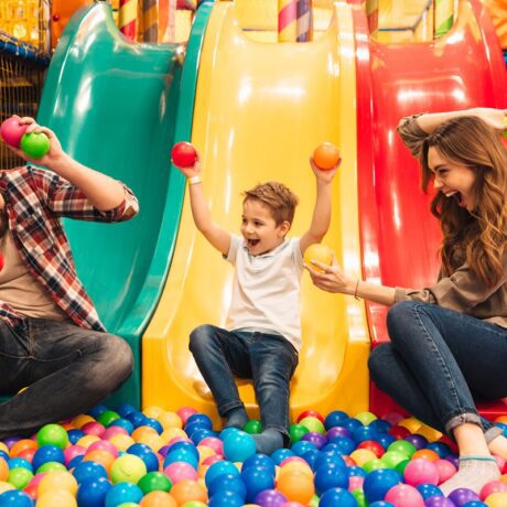 O familie fericită care se joacă într-un loc special în care sunt bile de plastic