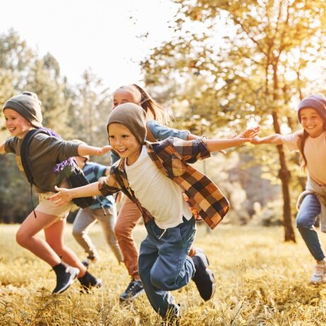 Un grup de copii fericiți aleargă în natură