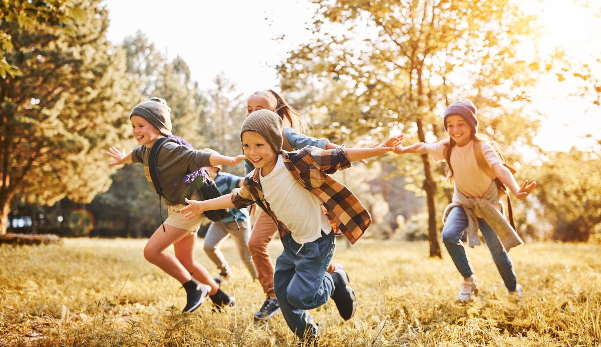 Un grup de copii fericiți aleargă în natură