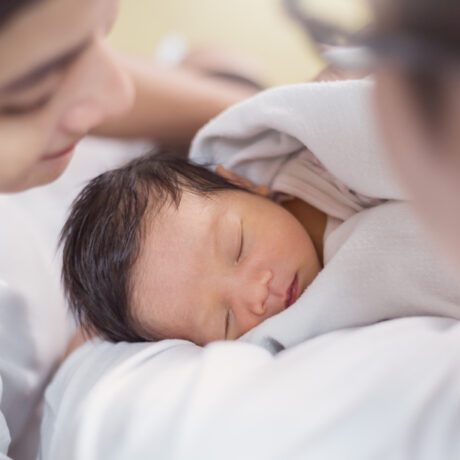 Bebeluș nou-născut lânga mama lui ține ochii închiși