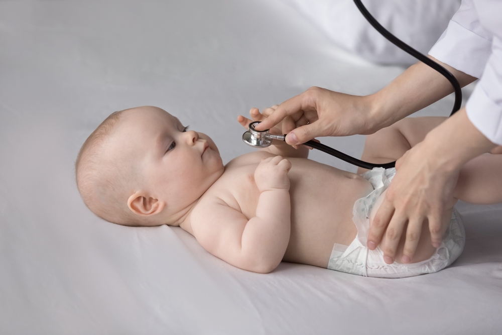 Bebeluș care privește un stetoscop ce aproape îl atinge în zona plămânilor