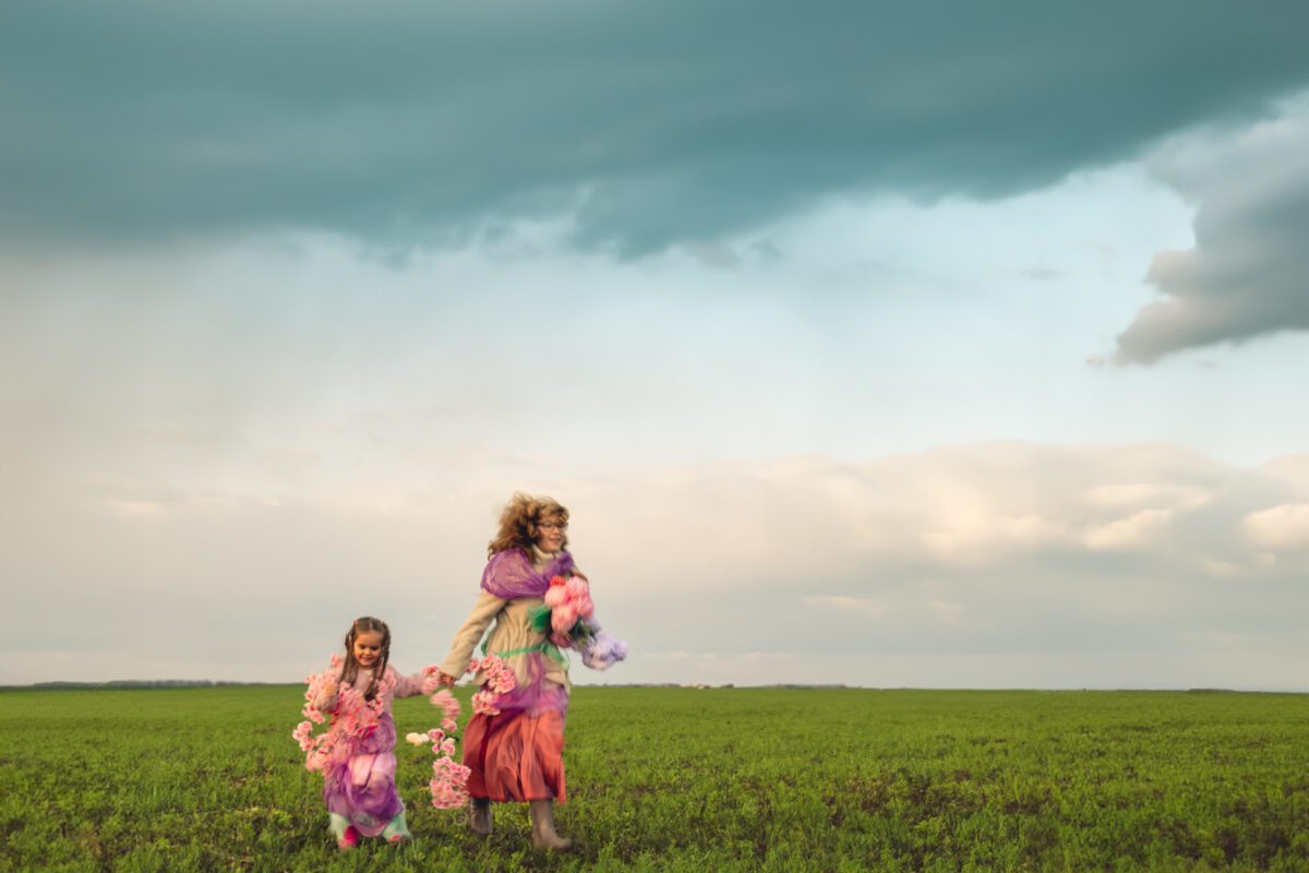 O mamă care se plimbă de mână cu fiica ei pe un câmp