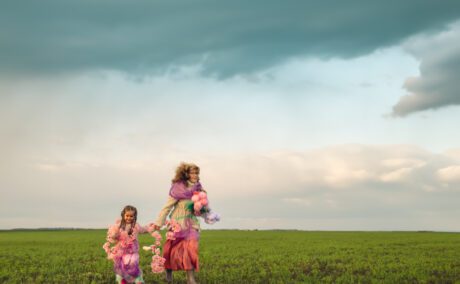 O mamă care se plimbă de mână cu fiica ei pe un câmp