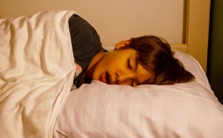 băiat care doarme cu gura deschisă în așternuturi albe