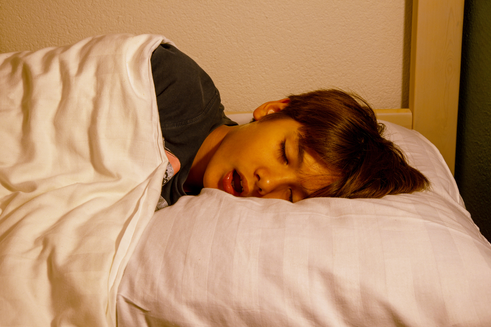 băiat care doarme cu gura deschisă în așternuturi albe