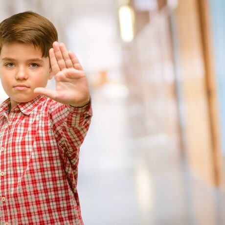 Băiatul stă cu mâna întinsă pentru a pune stop agresiunilor
