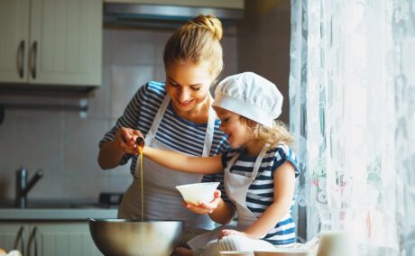 O mămică care stă în bucătărie și gătește alături de fetița ei
