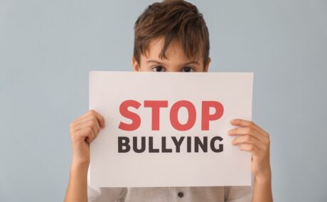 Băiat ține în mână o foaie cu stop bullying