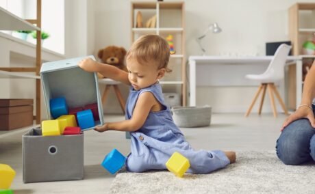 Un copil independent care își strânge singur cuburile din cameră