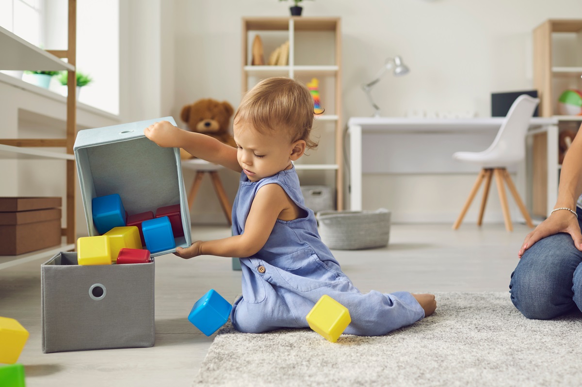 Un copil independent care își strânge singur cuburile din cameră