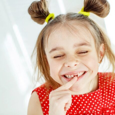 O fetiță frumoasă care arată a cameră faptul că a pierdut un dinte de lapte