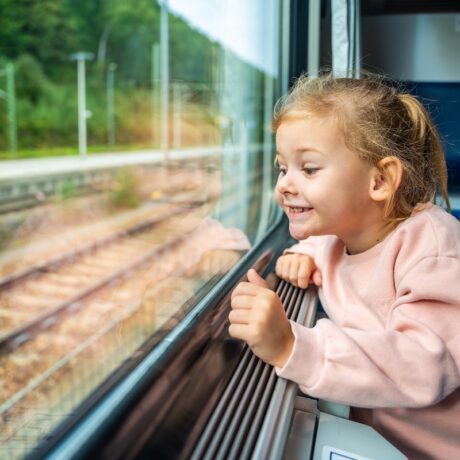 Fetița se uită bucuroasă pe geamul trenului