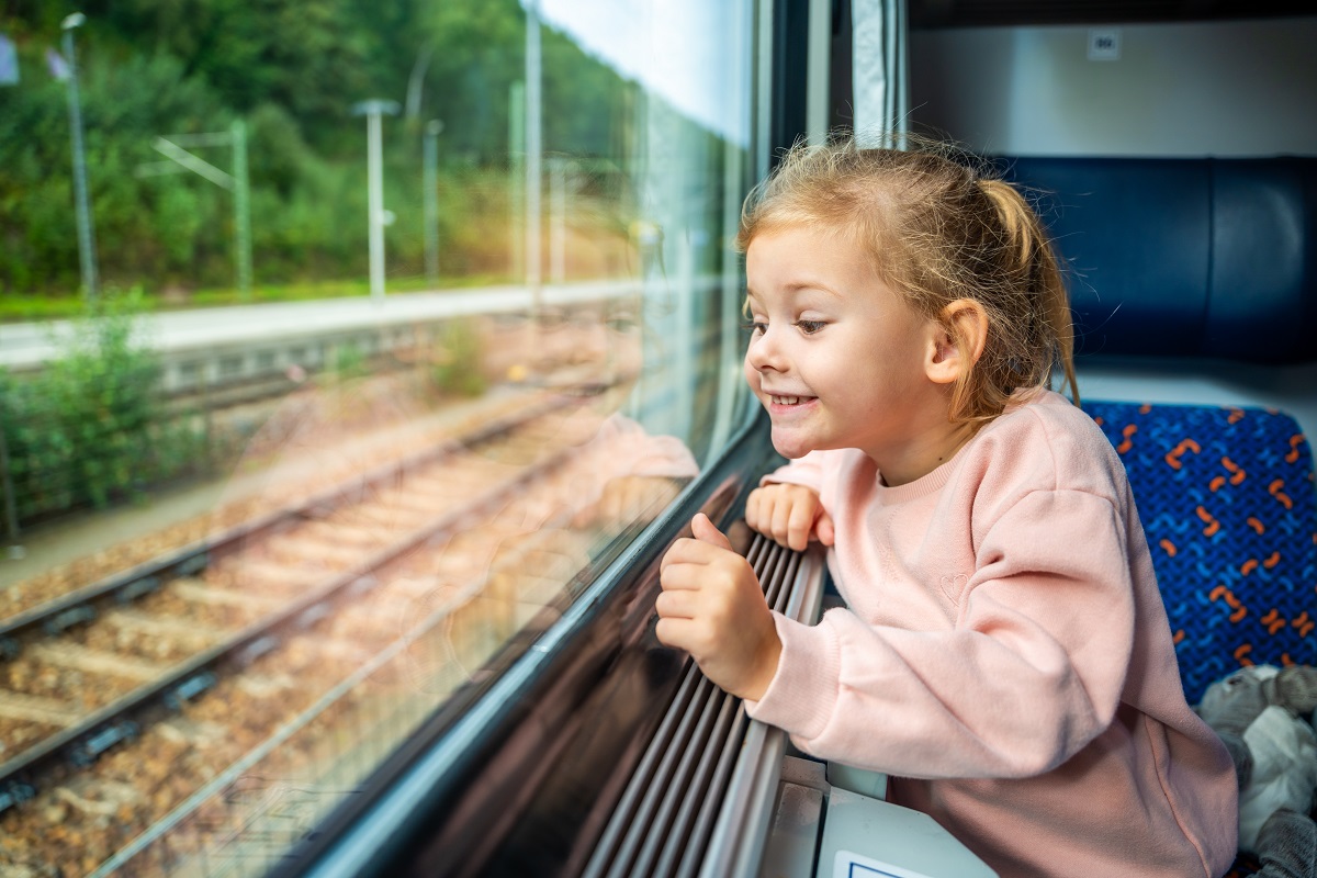 Fetița se uită bucuroasă pe geamul trenului