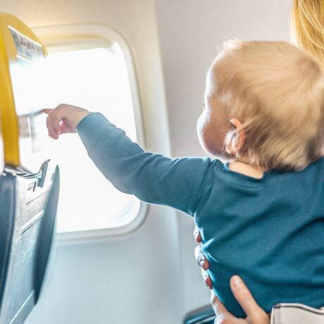 Mama se uită împreună cu bebelușul pe geamul avionului