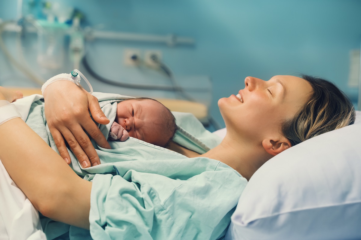 Proaspăta mămică își ține nou-născutul în brațe