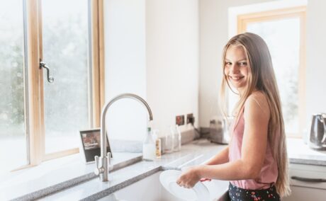 O adolescentă care spală vasele pentru a-și ajuta părinții