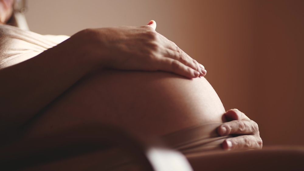 O femeie însărcinată cu mâna pe burtă