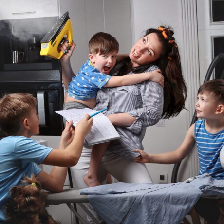 O mamă care stă cu cei trei copii în timp ce încearcă să și calce