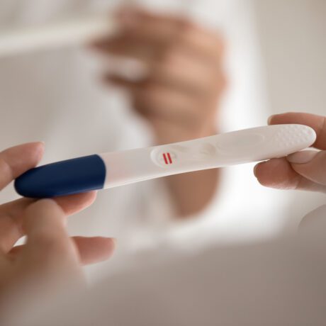 O femeie care are în mână un test de sarcină