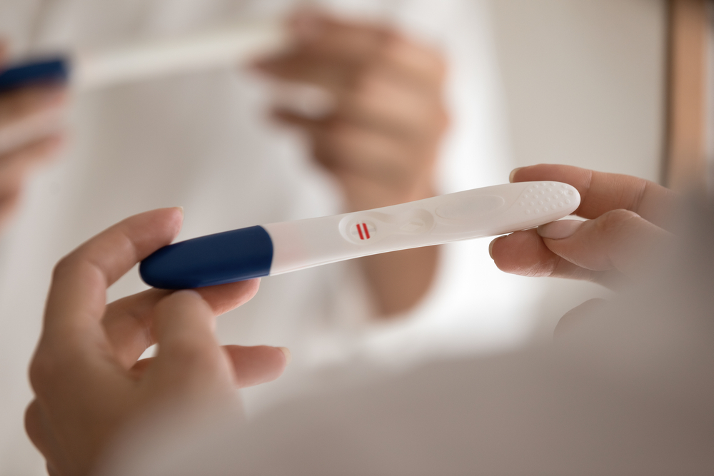 O femeie care are în mână un test de sarcină