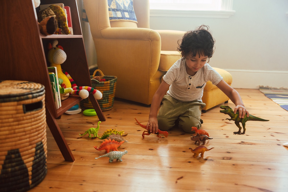 Băiețel se joacă singur cu dinozaurii