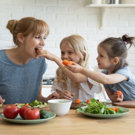 Două fetițe îi dau mamei să mănânce și ea morcovi