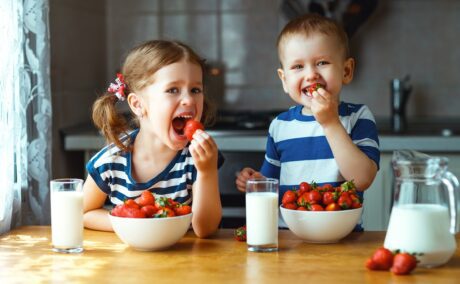 Fetiță și băiețel mănâncă căpșuni