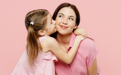 O fetiță care își îmbrățișează mama și o sărută pe obraz pentru a ilustra limbajl iubirii la copii