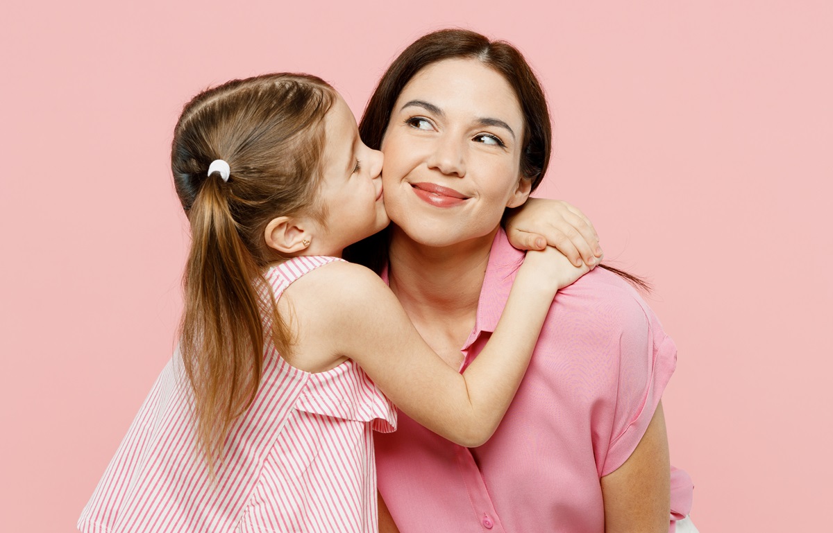 O fetiță care își îmbrățișează mama și o sărută pe obraz pentru a ilustra limbajl iubirii la copii