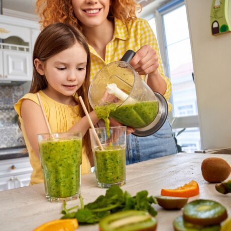 Mama și fata pregătesc smoothie din legume cu frunze verzi
