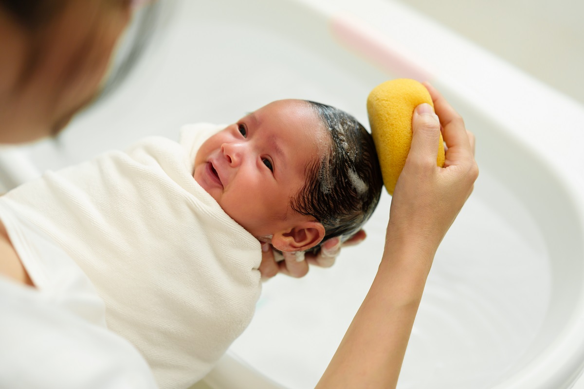 Mama spală bebelușul pe cap