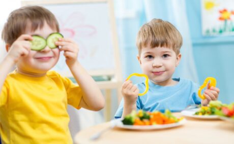 Doui băieței care stau la masă și mânâncă superalimente recomandate pentru dieta unui copil