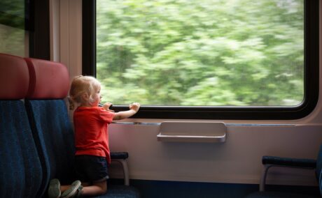 Copil stă și se uită pe geamul trenului