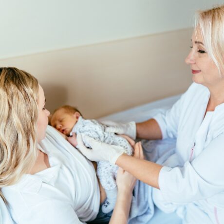 Proaspăta mama este ajută de un consultant în lactație să atașeze bebelușul la sân