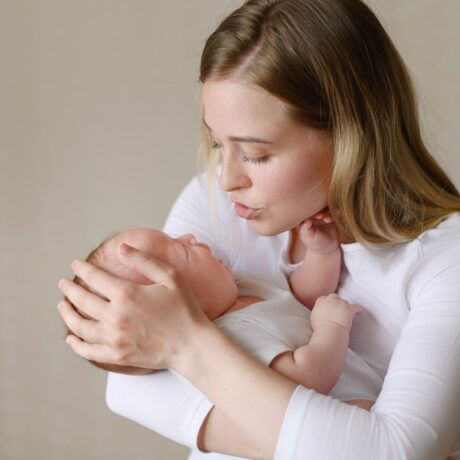 Mama își ține bebelușul în brațe și încearcă să-l calmeze din plâns