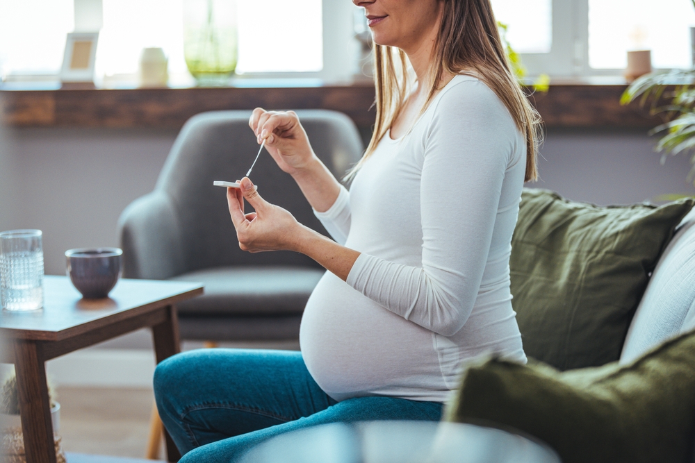 Femeie însărcinată care face un test într-o cameră însorită