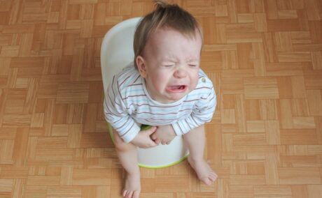 Bebeluș stă pe oliță și plânge