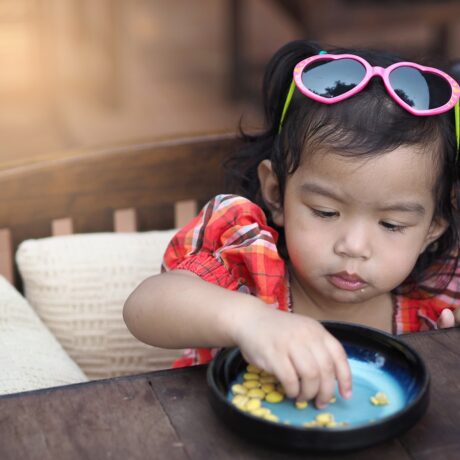 O fetiță frumoasă care mânâncă alune de pe o farfurie albastră
