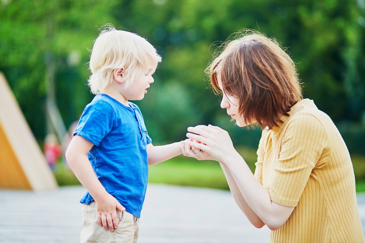 O mamă care încearcă să scoată așchia de sub piele din mâna băiețelului său