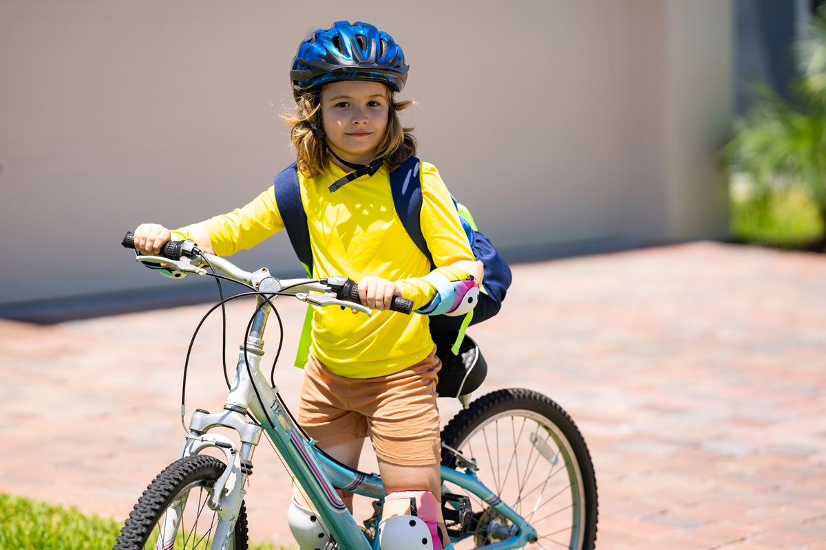 Un băiețel care poartă echipament de protecție și merge pe prima lui bicicletă