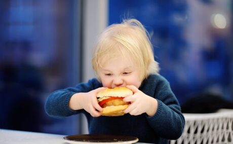 Copil mănâncă un hamburger