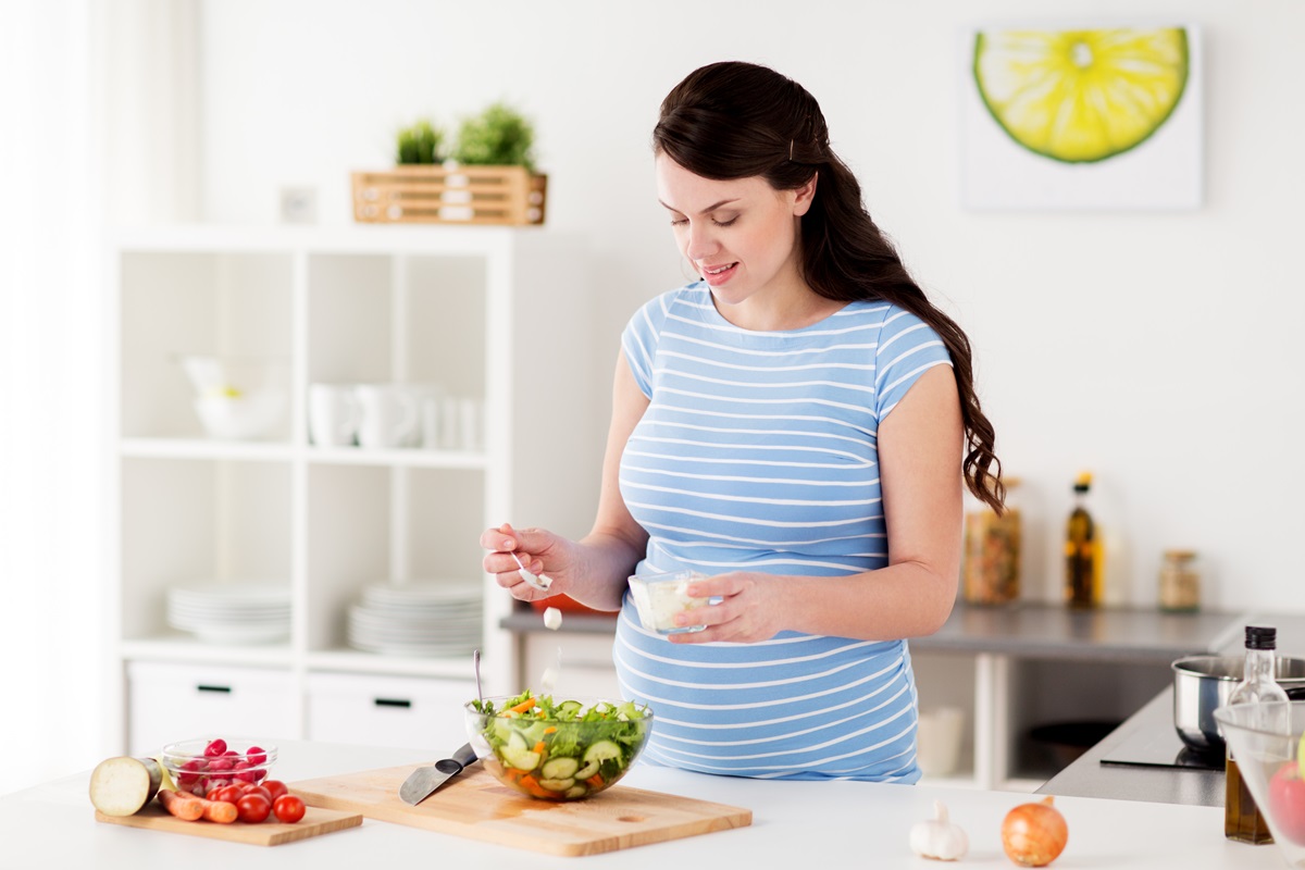 O femeie însărcinată care prepară o salată cu brânză de capră