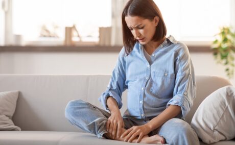 Gravidă stă pe pat și se scarpină pe picioare