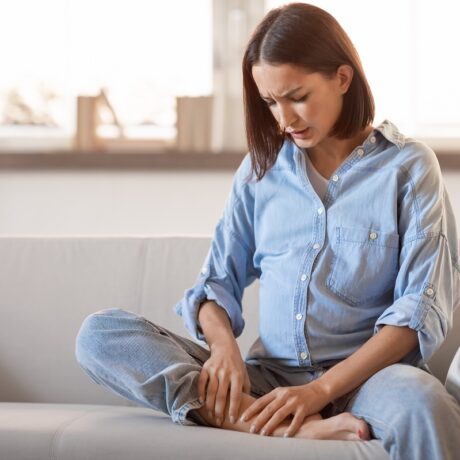 Gravidă stă pe pat și se scarpină pe picioare